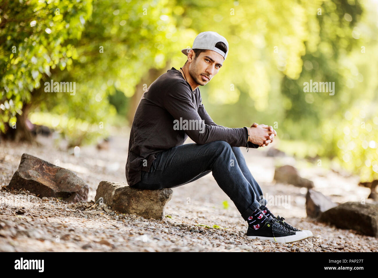 Retrato de joven con una gorra de béisbol sentado en la naturaleza Foto de stock