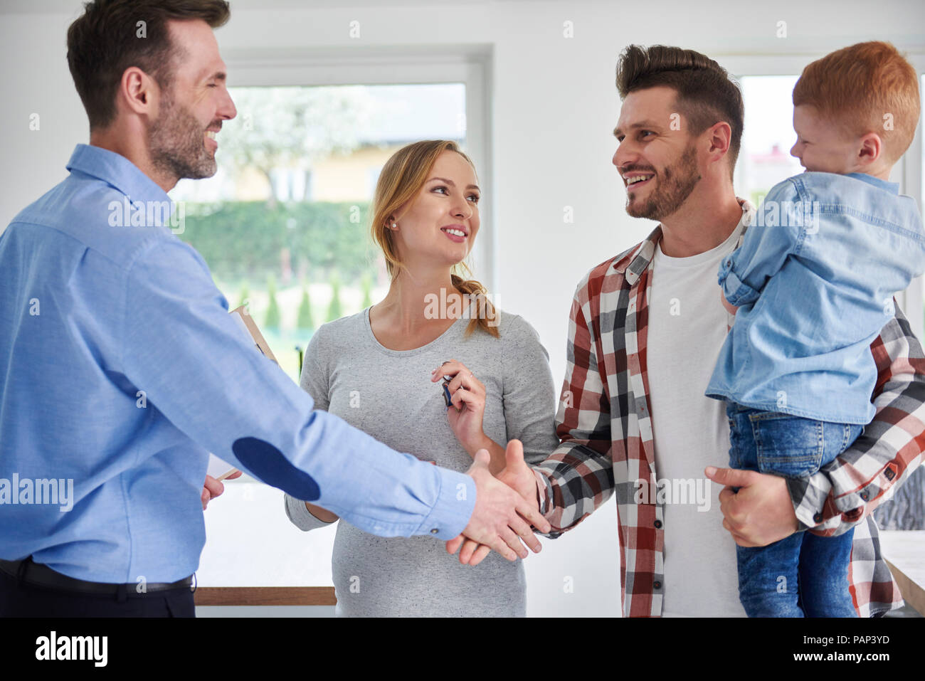 La familia real estate agent y un apretón de manos en el nuevo apartamento Foto de stock