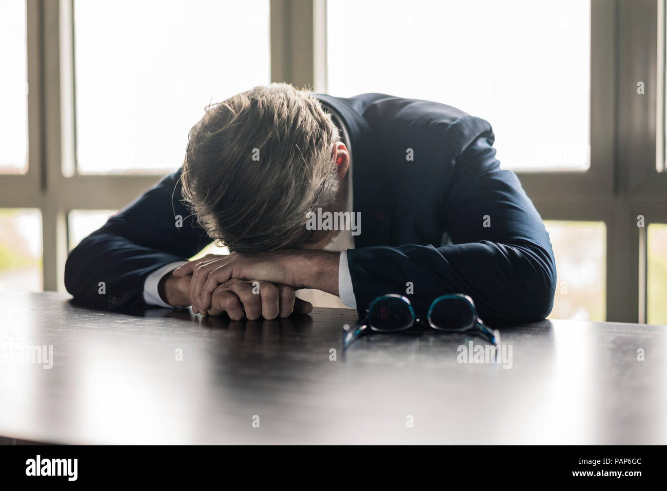 Empresario maduro descansando su cabeza sobre la mesa Foto de stock
