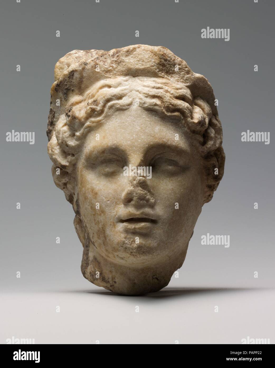 Cabeza de mármol de una mujer con diadema. Cultura: La Romana. Dimensiones: H. 5 7/8 in. (14,9 cm). Fecha: 1ª o 2ª siglo A.D.. Esta cabeza probablemente proviene de una pequeña estatua de una diosa o una personificación femenina. Aunque la mano de obra parece ser Romano, el estilo de la cara y el arreglo del cabello se derivan de Tardío y Clásico Temprano modelos helenísticos. Museo: Museo Metropolitano de Arte, Nueva York, Estados Unidos. Foto de stock