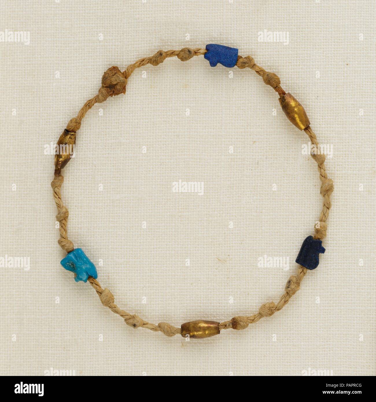 Brazalete con ojo wedjat amuletos y abalorios de barril. Dimensiones: Diam. ca. 3,8 cm (1 1/2"). Dinastía: Dinastía tardía 21. Fecha: ca. 1000-945 A.C. Encadenan en este hilo único de 2 capas de cordón de lino son tres cordones de barril de oro alternando con ojo wedjat amuletos, uno de loza y dos de cristal azul oscuro. El wedjat amuletos representan el sanado el ojo del dios halcón Horus, un poderoso símbolo de protección y regeneración. Este es uno de los cuatro pulseras encontrado alrededor de la muñeca izquierda de la momia Henettawy. Museo: Museo Metropolitano de Arte, Nueva York, Estados Unidos. Foto de stock