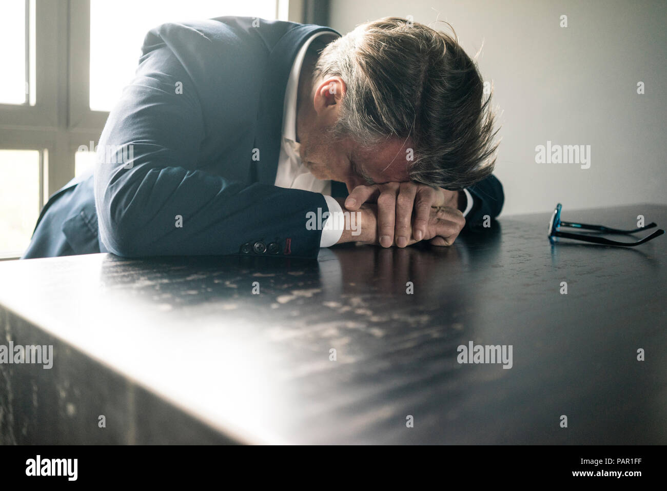 Empresario maduro descansando su cabeza sobre la mesa Foto de stock