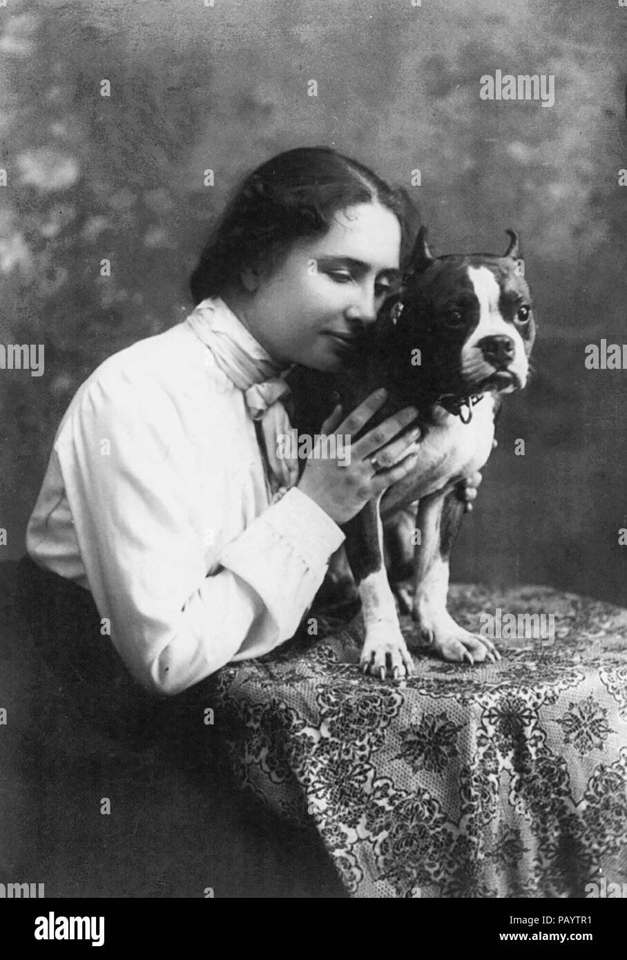 Helen Keller, retrato de tres cuartos de longitud., sentado, mirando hacia la derecha; celebración de perro en la mesa, circa 1902 Foto de stock