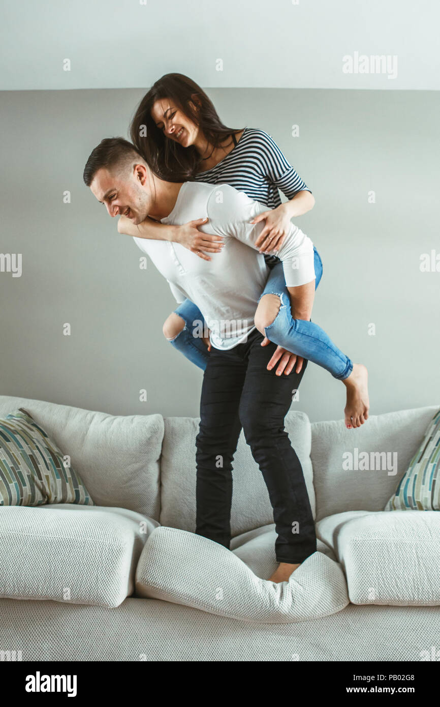 Retrato de la hermosa joven pareja gracioso hombre mujer enamorada  divirtiéndose de pie sobre la cama piggyback adentro en casa, teñido con  filtros Fotografía de stock - Alamy