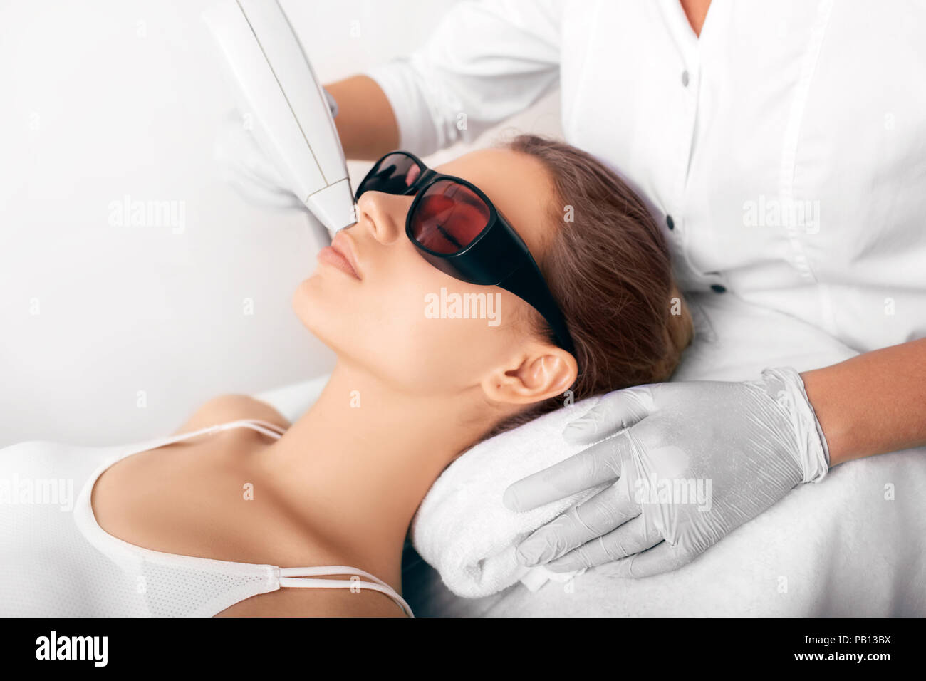 Sonriente mujer cliente en gafas protectoras en el procedimiento de  depilación. Eliminación del vello con láser en la mano femenina. Concepto  de cosmetología profesional Fotografía de stock - Alamy