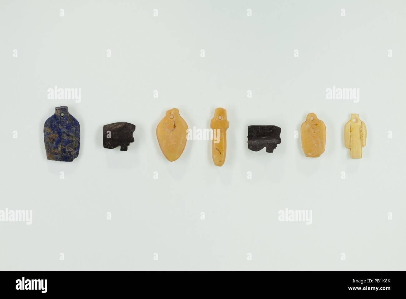 Grupo de 7 amuletos. Dimensiones: H. 0,6 a 1,4 cm. Dinastía: Dinastía 21. Fecha: ca. 1070-945 A.C. Este grupo de objetos se encuentra en la garganta de la señorita Djedmutesankh, roscado junto en un apretado manojo. Ahora hay 7 amuletos de diversos materiales: 2 placas, una incisión con la imagen de un hombre y el otro con una cría de ojos wedjat cobra; 2; 1 (papiro) wadj cetro; 1 el corazón; y 1 "nudo de Isis" (cíngulo empate). Otros dos amuletos, un corazón y un tallo de papiro, tanto de vidrio verde, se desintegró después de que fueran descubiertos. Véase 25.3.169A-I para los amuletos individuales. Para otros objetos foun Foto de stock