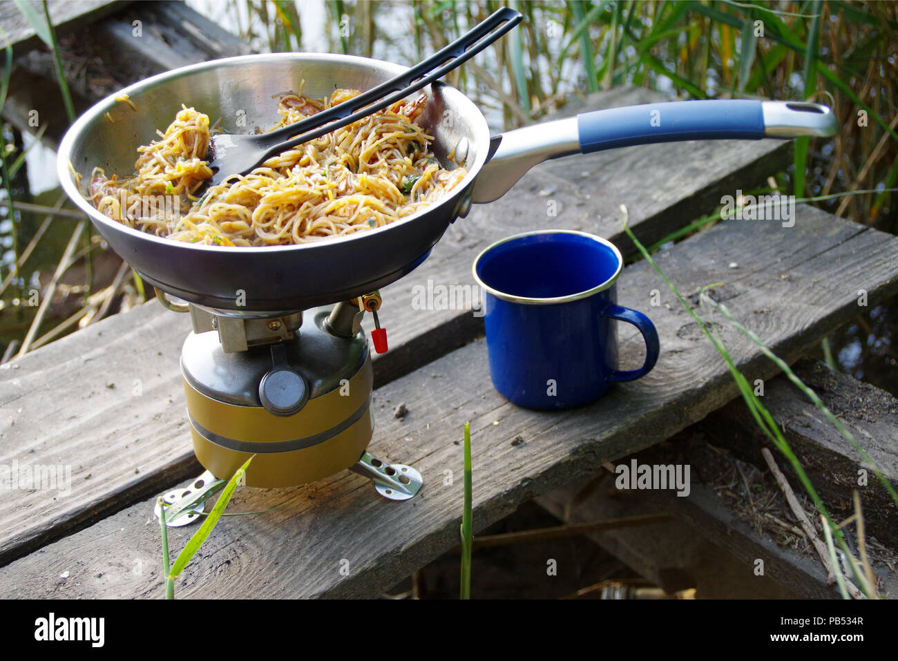 Camping alimentos decisiones. Pasta de pan en turista estufa a leña. Cocina  del campamento en la orilla del lago Fotografía de stock - Alamy