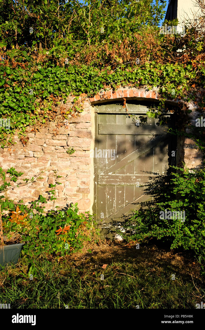 Julio de 2018 - La puerta secreta, un crecido jardín rural portada Foto de stock