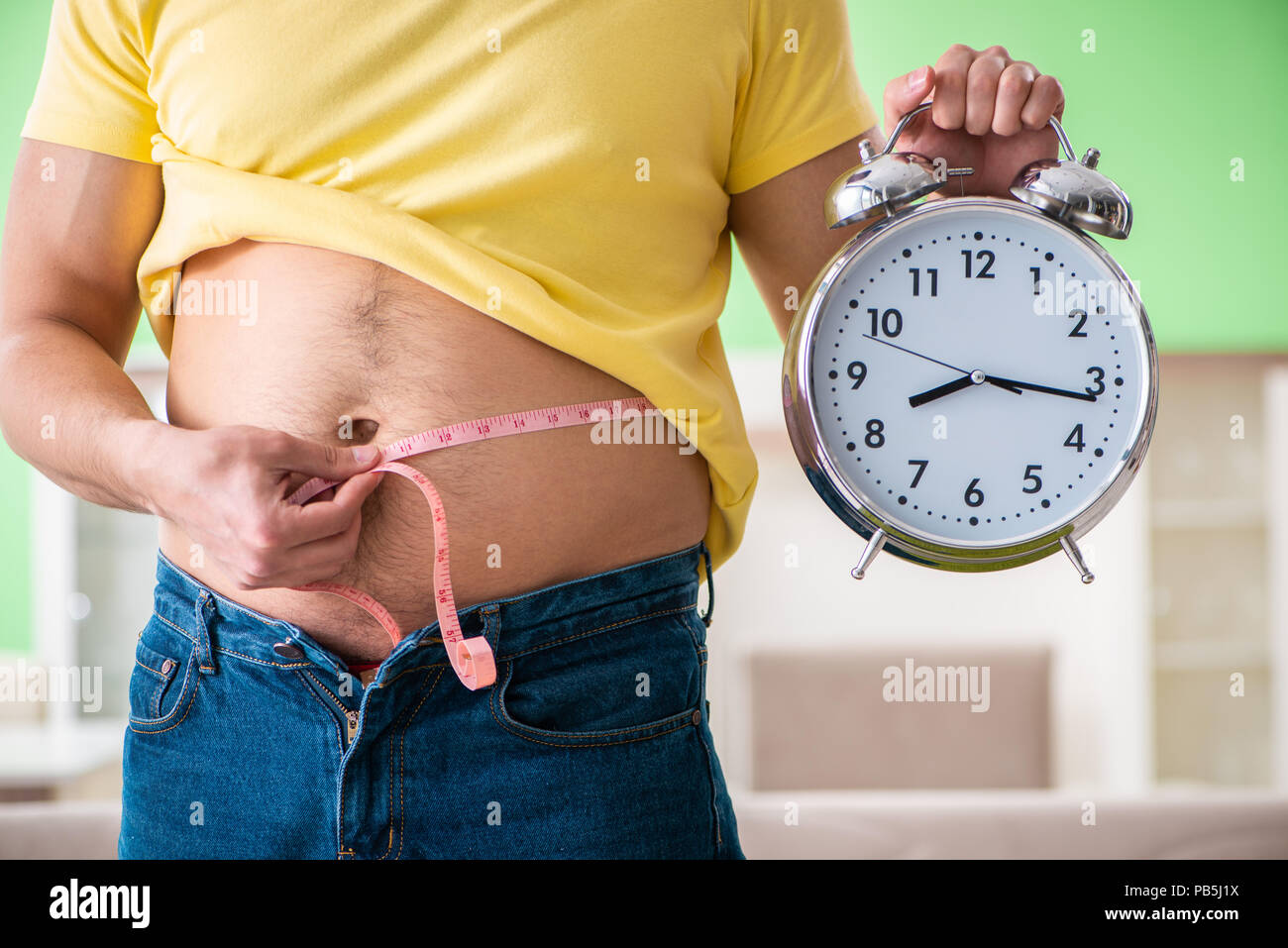 El hombre mide la grasa corporal con cinta de medir en concepto de gestión  del tiempo Fotografía de stock - Alamy