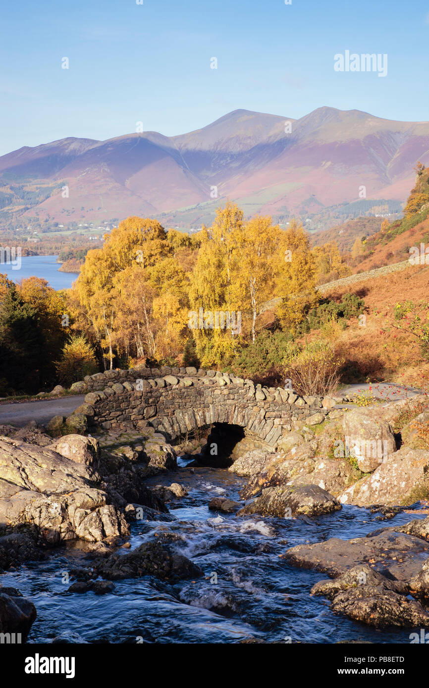 Ashness puente cruzar un arroyo de montaña y árboles en otoño en el Parque Nacional Lake District inglés Keswick Borrowdale Cumbria Inglaterra Gran Bretaña Foto de stock