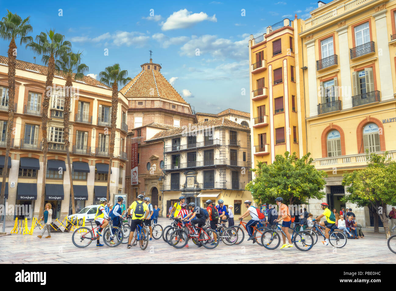 Escena de una calle con un grupo de turistas en bicicleta en el centro de la ciudad. Málaga, Andalucía, España Foto de stock