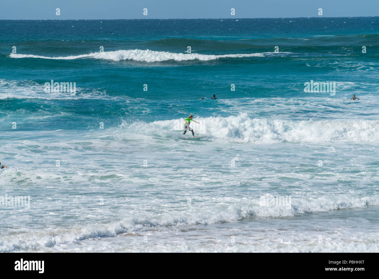 COOLANGATTA, AUSTRALIA - 10 de julio de 2018; la amplia playa de surf con surfistas cabalgando por ola blanca espuma con el profundo mar azul turquesa detrás Foto de stock