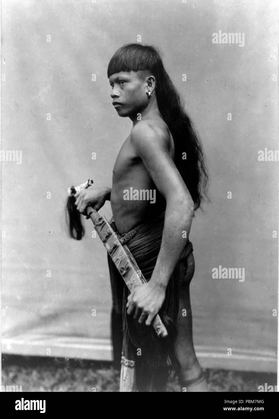Hombre Dyak, Singapur, de pie, de tres cuartos de longitud vertical hacia la izquierda, 1890-1925 Foto de stock