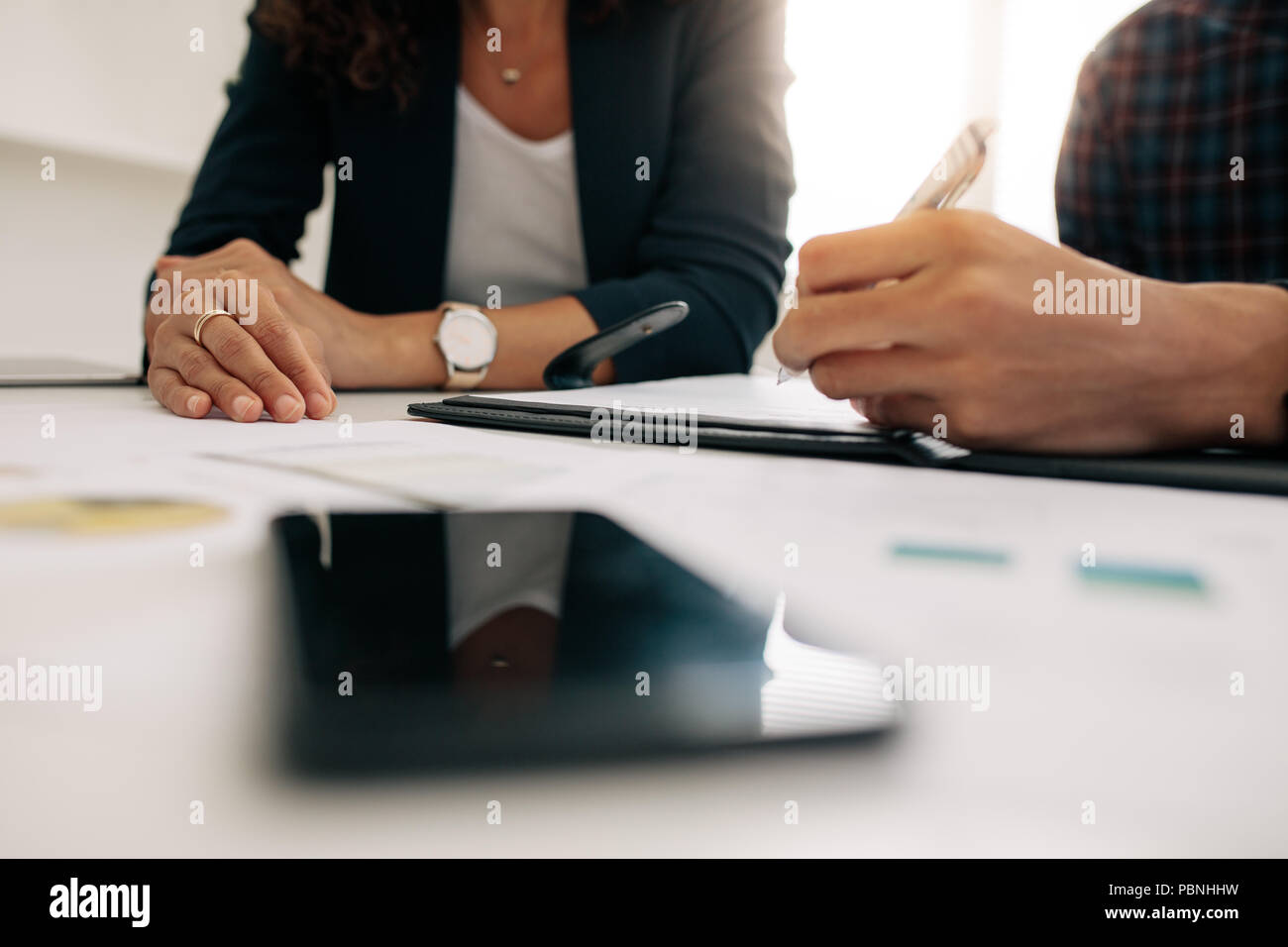 Cerrar centrados manos de colegas de negocios en una reunión discutiendo el trabajo. Empresaria en una reunión con un compañero de oficina. Foto de stock