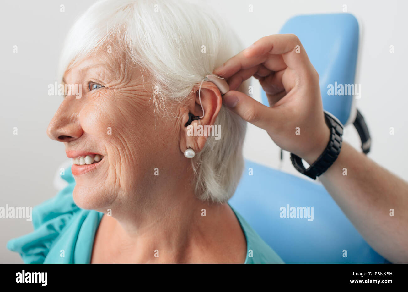 Ajuste de un audífono para un anciano mujer Foto de stock