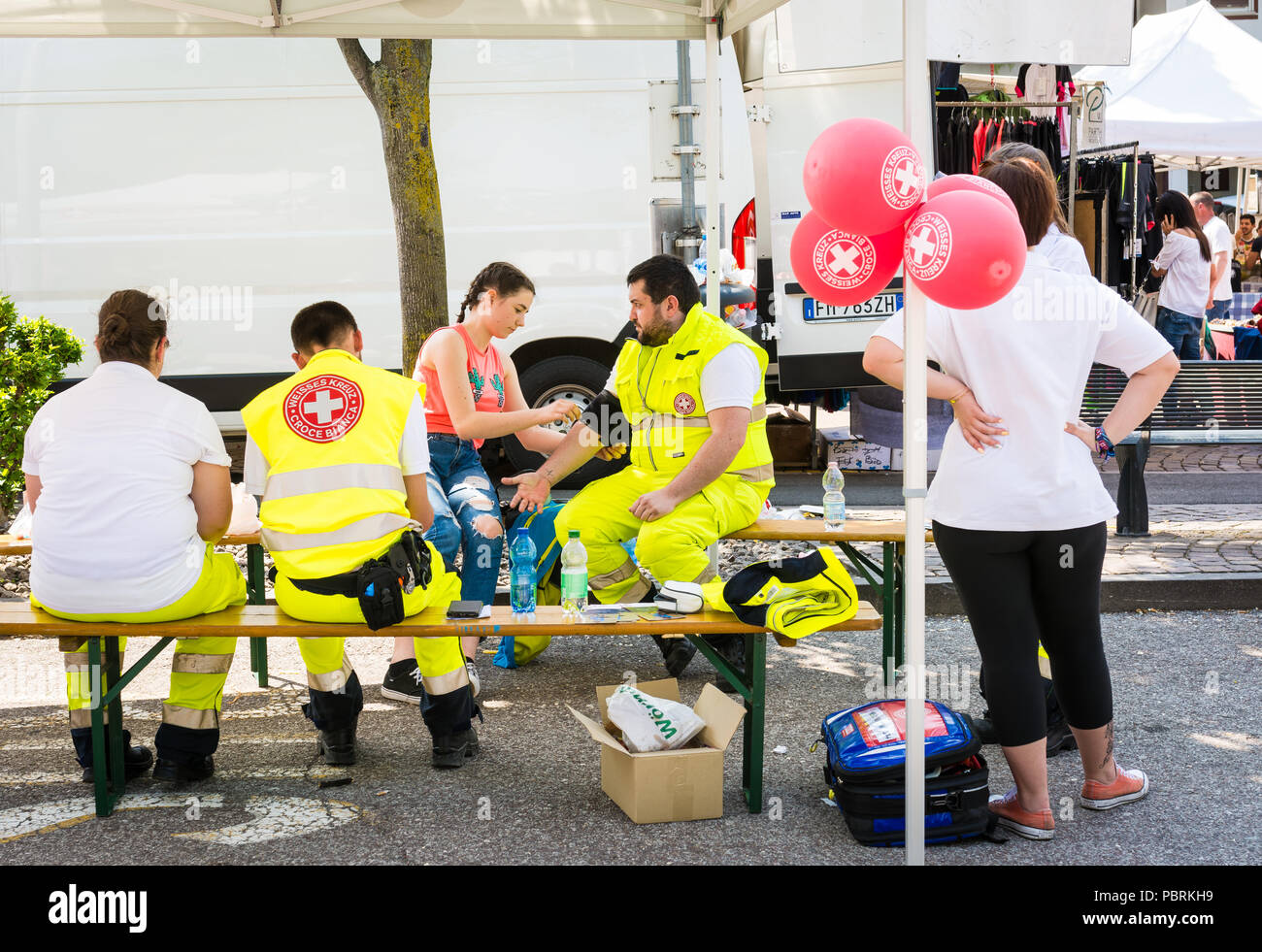 Stands promocionales sobre las actividades de la Cruz Roja, venta de gadgets y uniformes de la Cruz Roja Italiana - Cruz Roja Trentino Alto Adige, en Bolzano, Italia Foto de stock