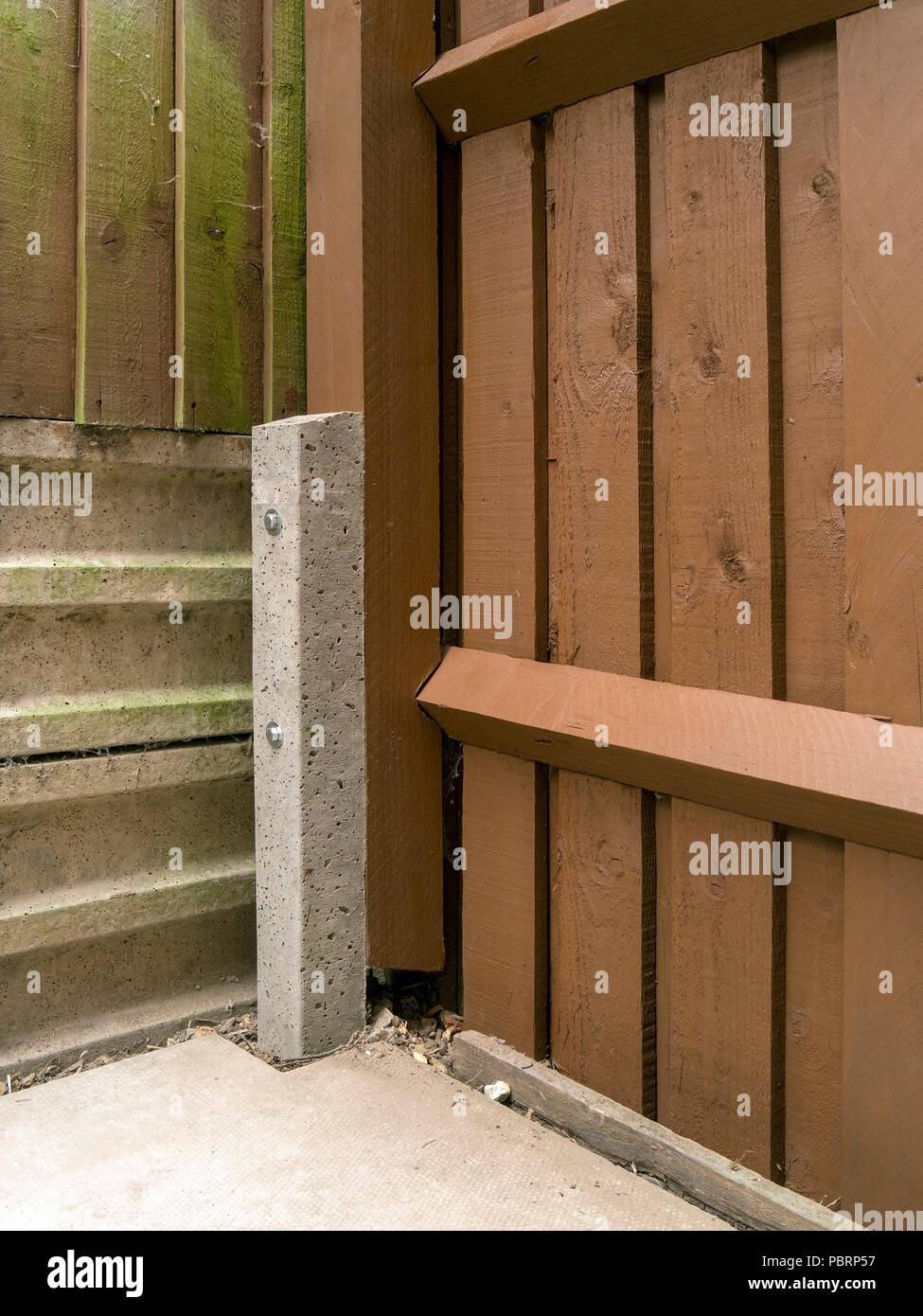 Concreto reforzado "padrino" vallado spur utilizado para reparar un poste de madera y rampa valla con cubos Foto de stock