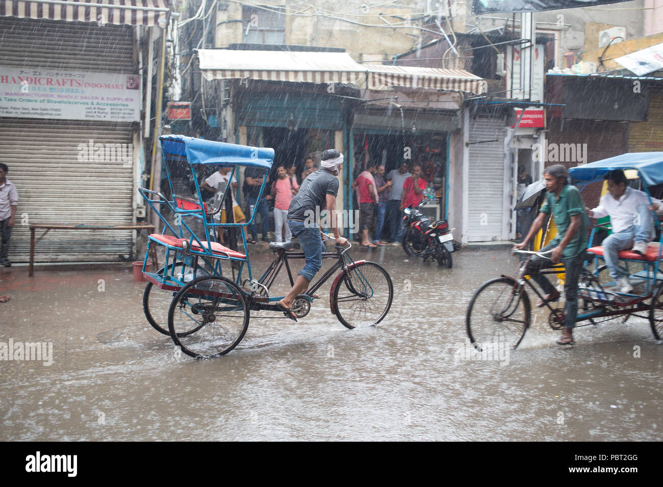 Rickshaws de bicicleta tratando de conseguir a través de las calles inundadas durante las lluvias del monzón en Nueva Delhi, India. Foto de stock
