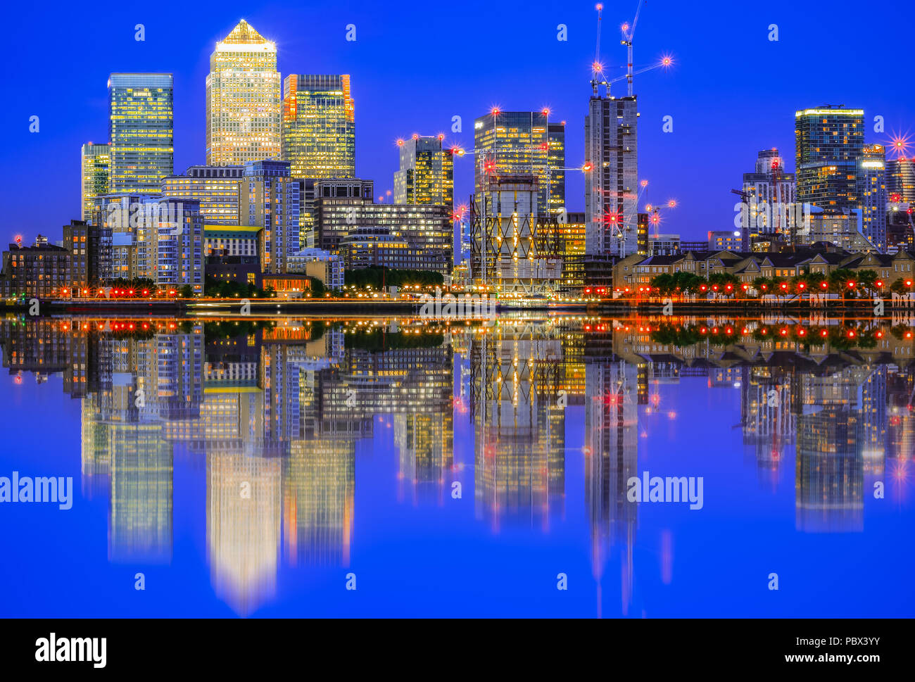 Paisaje iluminado en Canary Wharf y su reflejo desde el río Támesis, un importante distrito de negocios en el East London Foto de stock