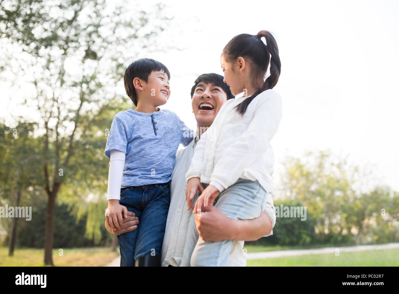 Joven alegre familia china jugar afuera Foto de stock