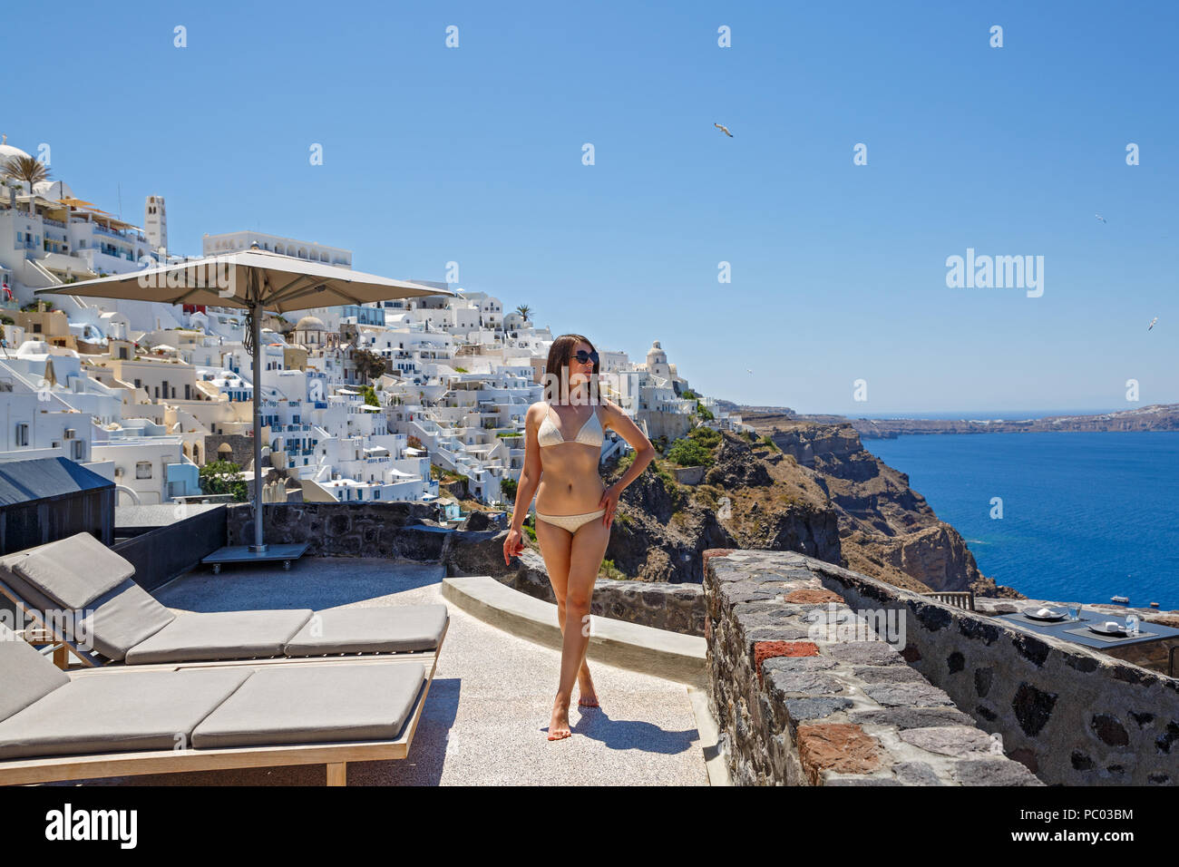 Mujer joven tomando sol en traje de baño, la isla de Santorini, Grecia Foto de stock