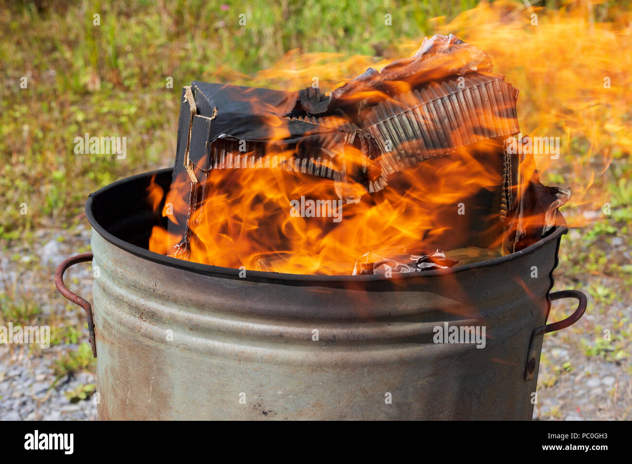 La quema de residuos de papel y cartón en el pequeño jardín incinerador Foto de stock