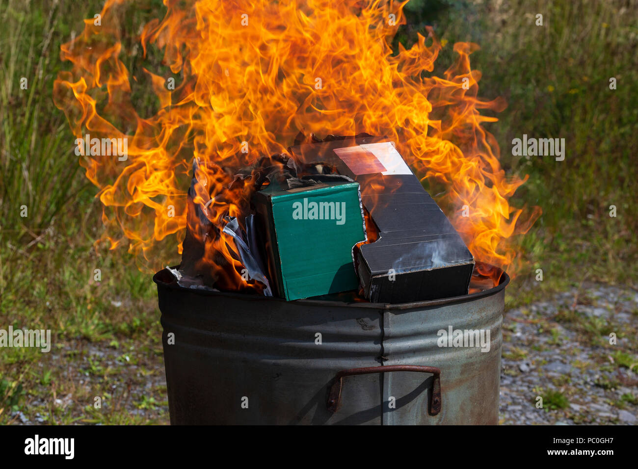 La quema de residuos de papel y cartón en el pequeño jardín incinerador Foto de stock