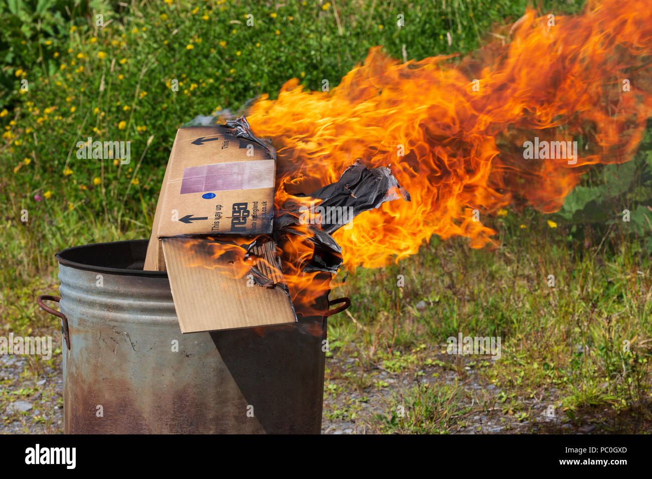 La quema de residuos de papel y cartón en el pequeño jardín incinerador Foto de stock