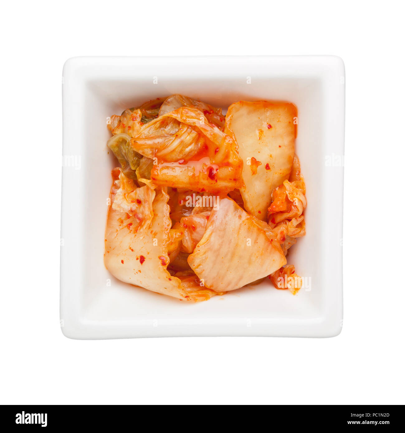 El kimchi en un recipiente cuadrado aislado sobre fondo blanco. Foto de stock