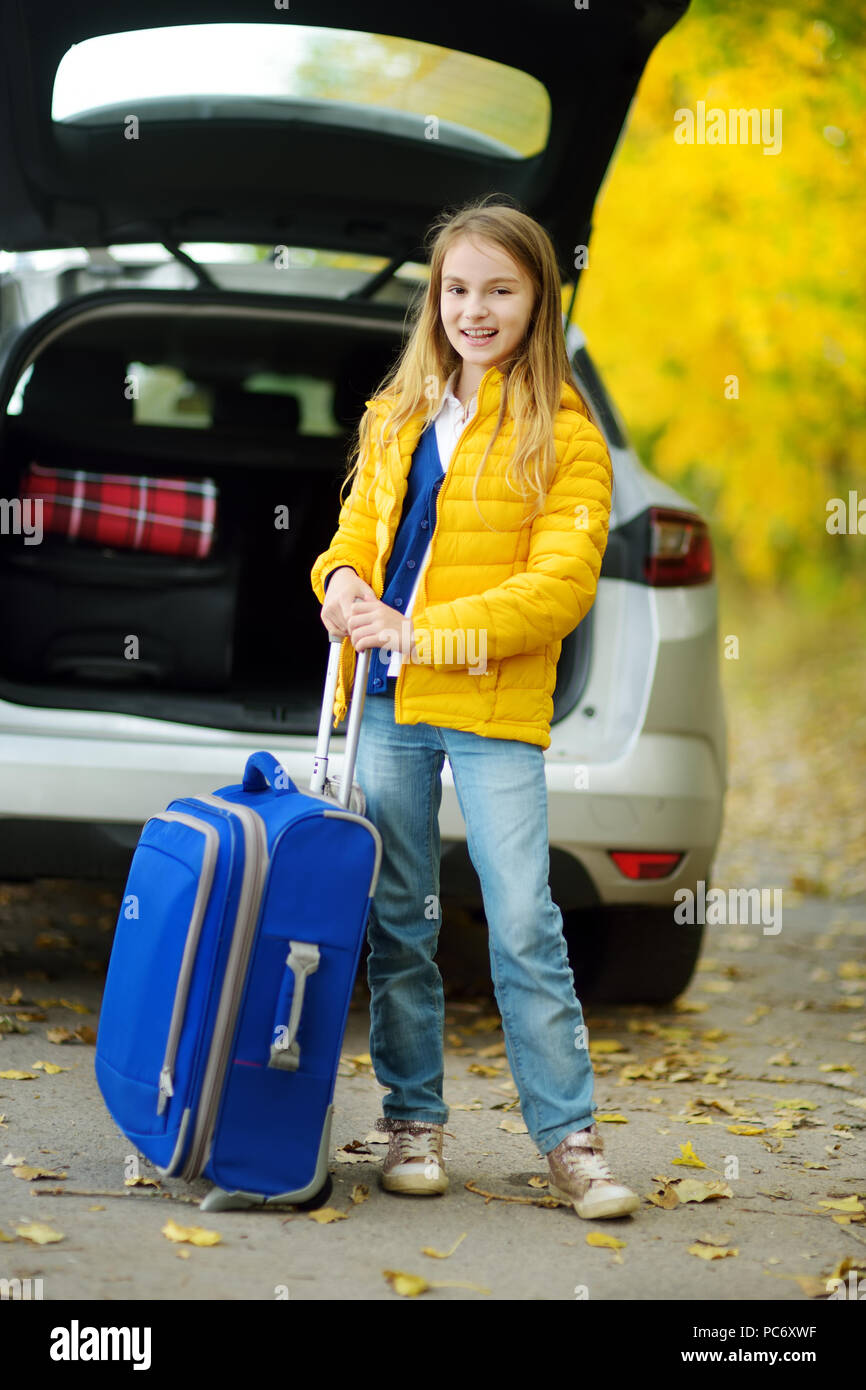 Adorable chica con una maleta lista para ir de vacaciones con sus padres.  Niño mirando hacia adelante para un viaje por carretera o viajes. Vacaciones  de otoño en la escuela. Actrav Fotografía