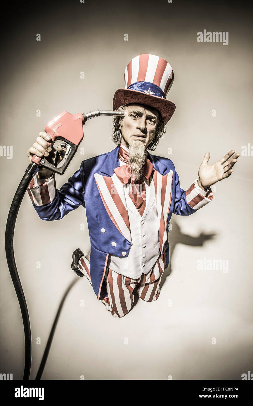 El Tío Sam de pie con una bomba de gas nozzel celebró en frente de él. Captura conceptual representando la adicción al petróleo americano / gas / petróleo. Foto de stock