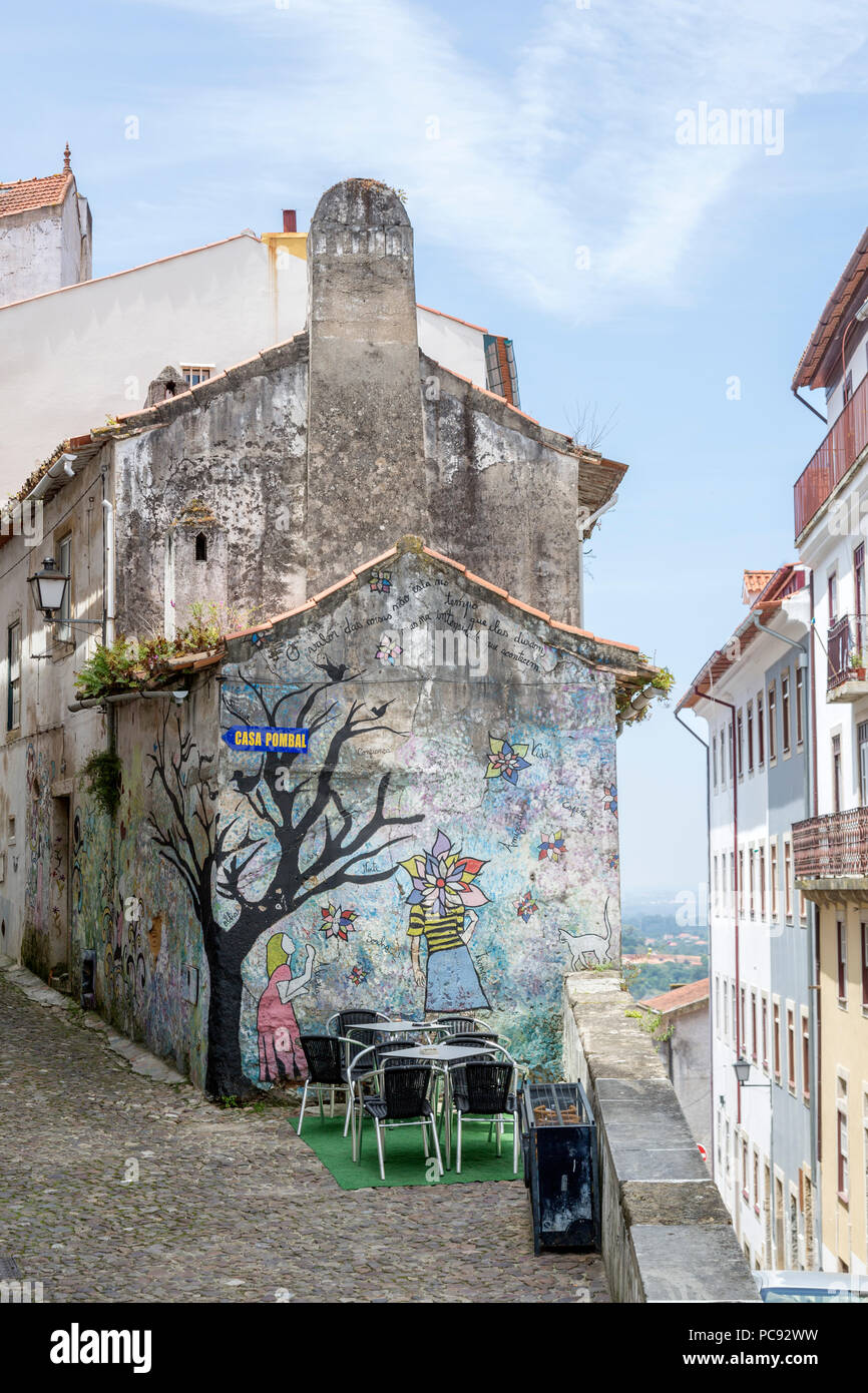 Linda área de asientos al aire libre, delante del edificio pintado artístico, en el histórico distrito junto a la Universidad de Coimbra, Portugal. Foto de stock