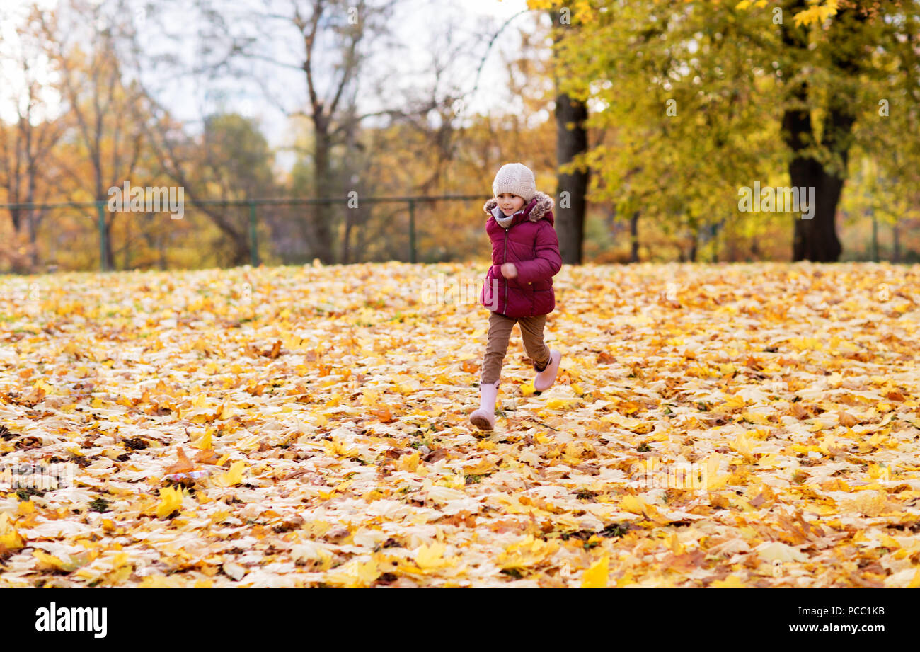 Feliz chica corriendo en el parque de otoño Foto de stock