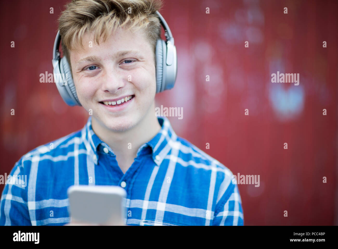 Retrato de niño adolescente usando auriculares inalámbricos y escuchar música en el entorno urbano Foto de stock