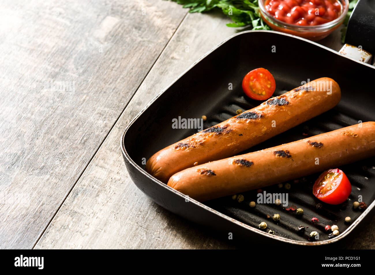 Salchichas asadas y salsa de tomate de mesa de madera Foto de stock