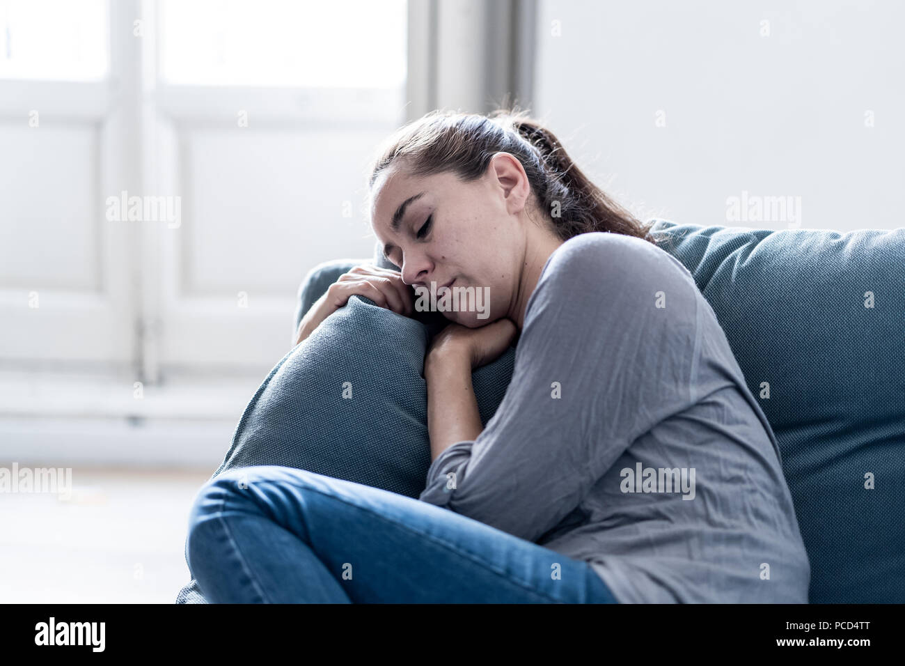 Joven Mujer latina atractiva acostado en casa salón sofá sentirse triste cansado y preocupado que sufren depresión en la salud mental, problemas y roto Foto de stock