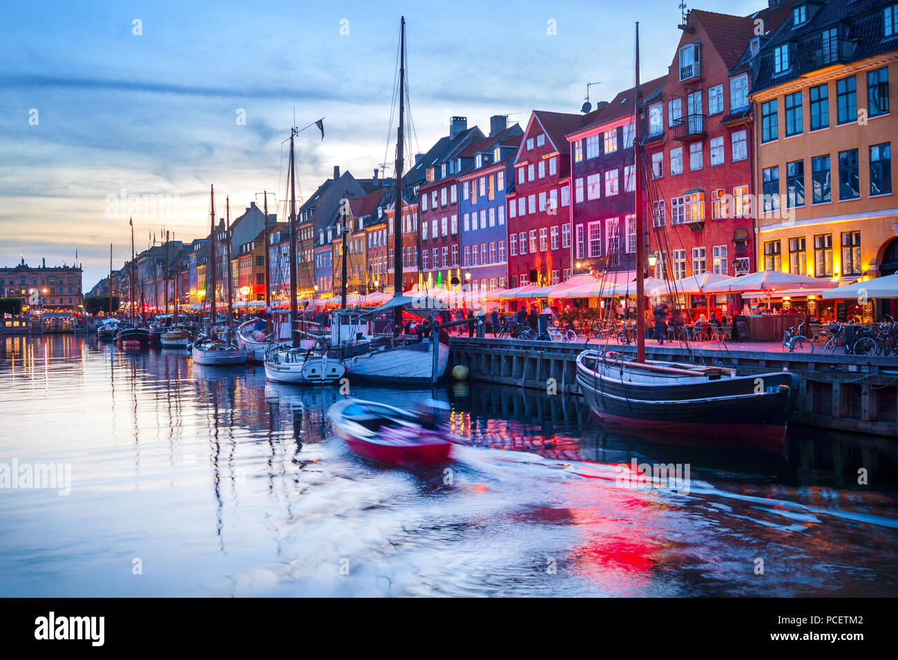 Escena nocturna con barcos amarrados en el puerto Nyhavn iluminado embankment, Copenhague, Dinamarca Foto de stock