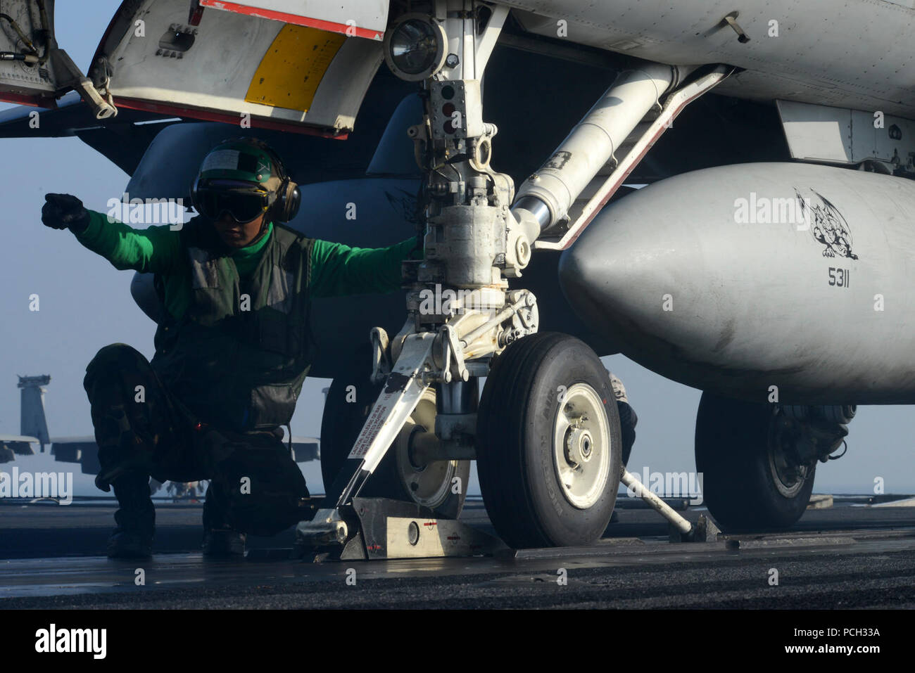 5ª Flota de EE.UU. ÁREA DE RESPONSABILIDAD (Ene. 22, 2013) - Aviacion Boatswain's Mate (equipos) de 3ª clase Salvador Santayana, desde San Diego, señales para el movimiento de avance de un F/A-18 C Hornet desde los dragones dorados de Strike Fighter Squadron (VFA) 192 sobre la cubierta de vuelo del portaaviones USS John C. Stennis (CVN 74). John C. Stennis se implementa en la Quinta Flota de EE.UU. área de responsabilidad la realización de operaciones de seguridad marítima, el teatro y los esfuerzos de cooperación en materia de seguridad a las misiones de apoyo a la Operación Libertad Duradera. Foto de stock