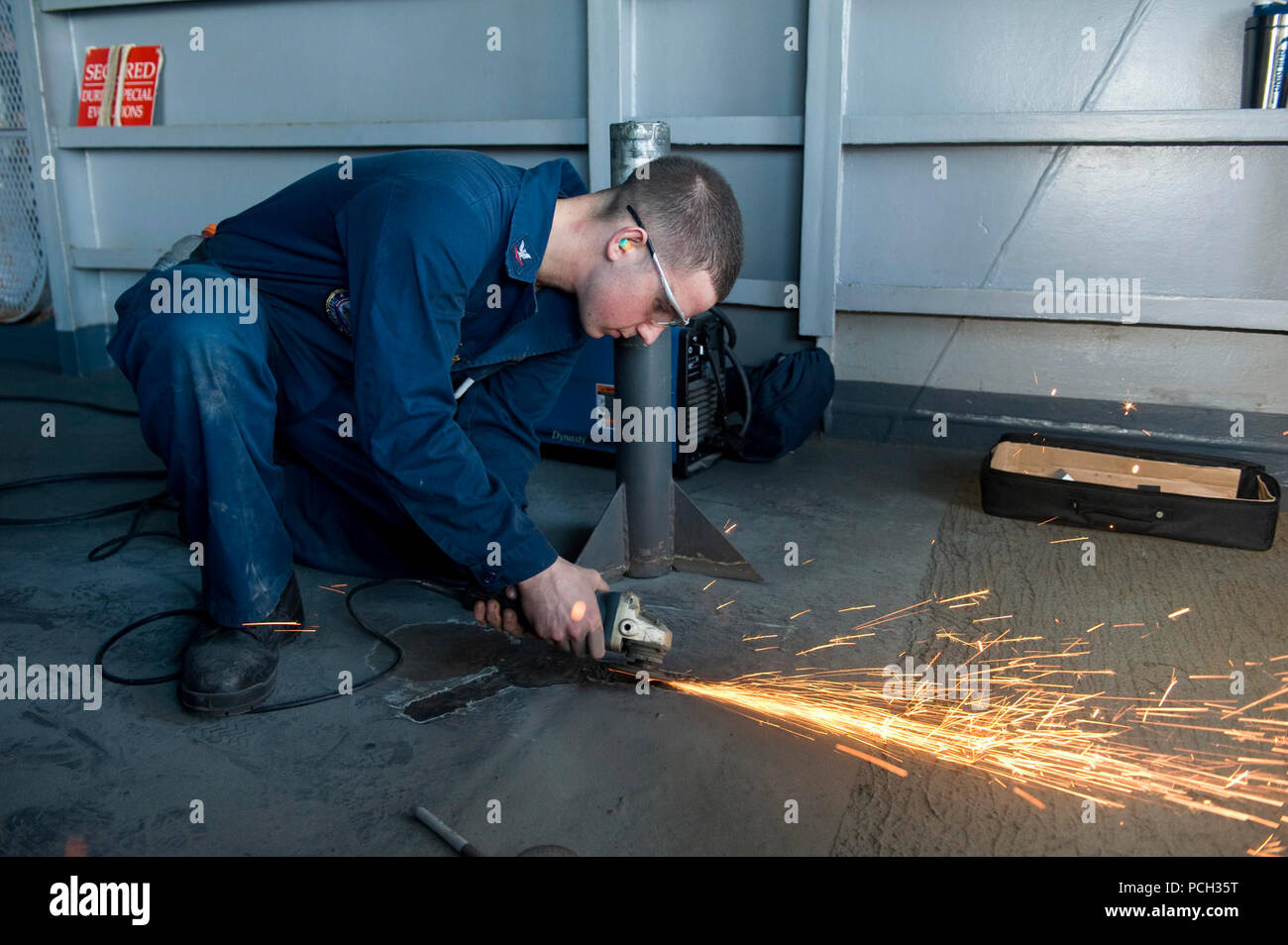 Mar Arábigo (Nov. 7, 2012), técnico de mantenimiento de casco de 3ª clase Ron Stocker sands herrumbre de la cubierta del portaaviones USS John C. Stennis (CVN 74). John C. Stennis se implementa en la Quinta Flota de EE.UU. área de responsabilidad la realización de operaciones de seguridad marítima, el teatro y los esfuerzos de cooperación en materia de seguridad a las misiones de apoyo a la Operación Libertad Duradera. Foto de stock