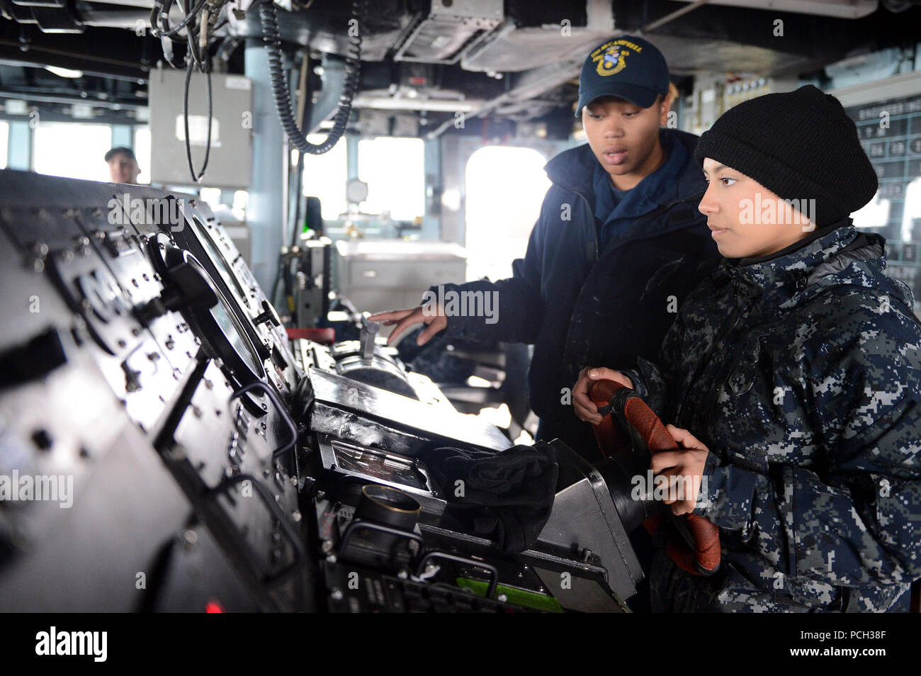 Las aguas al oeste de la península de Corea (18 de marzo de 2013) Boatswain's Mate de 3ª clase Brittany Chiles trenes Seaman Jessica Canas mientras le mans el timón a bordo de la clase Arleigh Burke de misiles guiados destructor USS McCampbell (DDG 85). McCampbell es parte de Destroyer Squadron 15, desplegadas a Yokosuka, Japón, y se están llevando a cabo para realizar el ejercicio bilateral Foal Eagle 2013 nación aliada con la República de Corea en apoyo de la seguridad regional y la estabilidad de la región del Pacífico Indo-Asia. Foto de stock