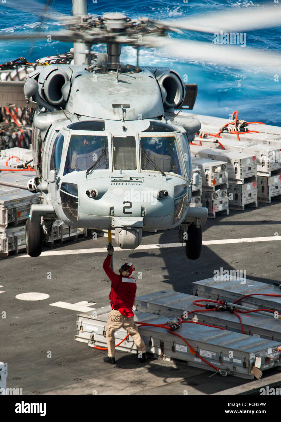 Océano Pacífico (28 Abril 2013) un miembro de la tripulación a bordo del transporte marítimo de carga seca, Comando Militar municiones buque USNS Richard E. Byrd (T-AKE 4) atribuye la carga a un MH-60S Sea Hawk helicóptero asignado a los indios de helicópteros de combate de mar (HSC) Escuadrón 6 mientras realizaban una reposición en alta mar con el portaaviones USS Nimitz (CVN 68). Nimitz y Carrier air wing 11 salió de San Diego para un despliegue en el Pacífico occidental. Foto de stock