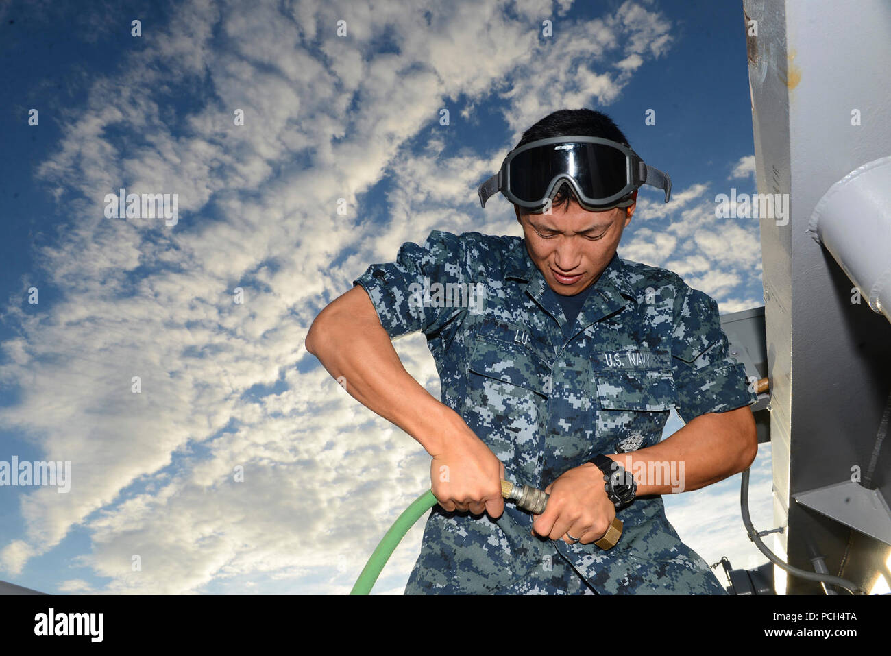 Aerotécnico Bo Lu, un inmigrante chino, refuerza un racor de manguera de aire a bordo del buque de asalto anfibio USS Bataan (LHD 5). Foto de stock
