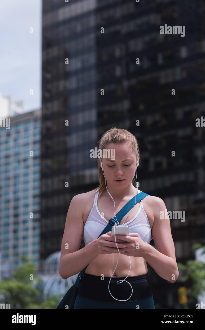 Mujer deportiva a través de teléfono móvil en la calle Foto de stock