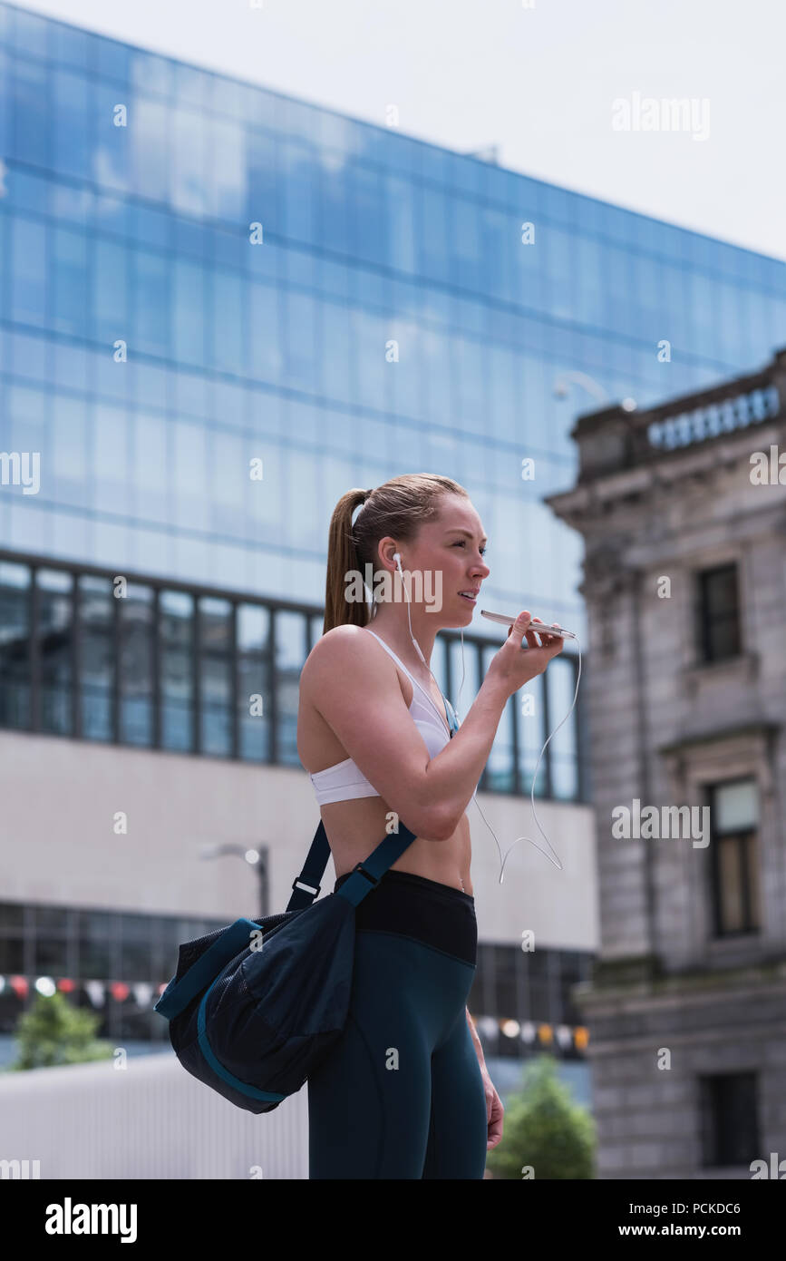 Mujer deportiva hablando por teléfono móvil en la calle Foto de stock