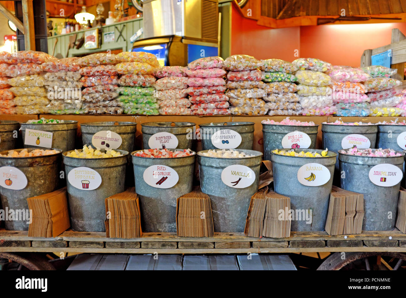 Taffy agua salada para la venta con piezas envuelto individual llenado baldes de hojalata que la gente pone en bolsas marrones y pagada por el peso. Foto de stock