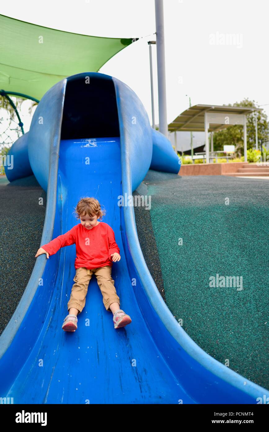 Un niño va hasta una diapositiva azul diseñado como un dugong, Cardwell, Queensland, Australia Foto de stock