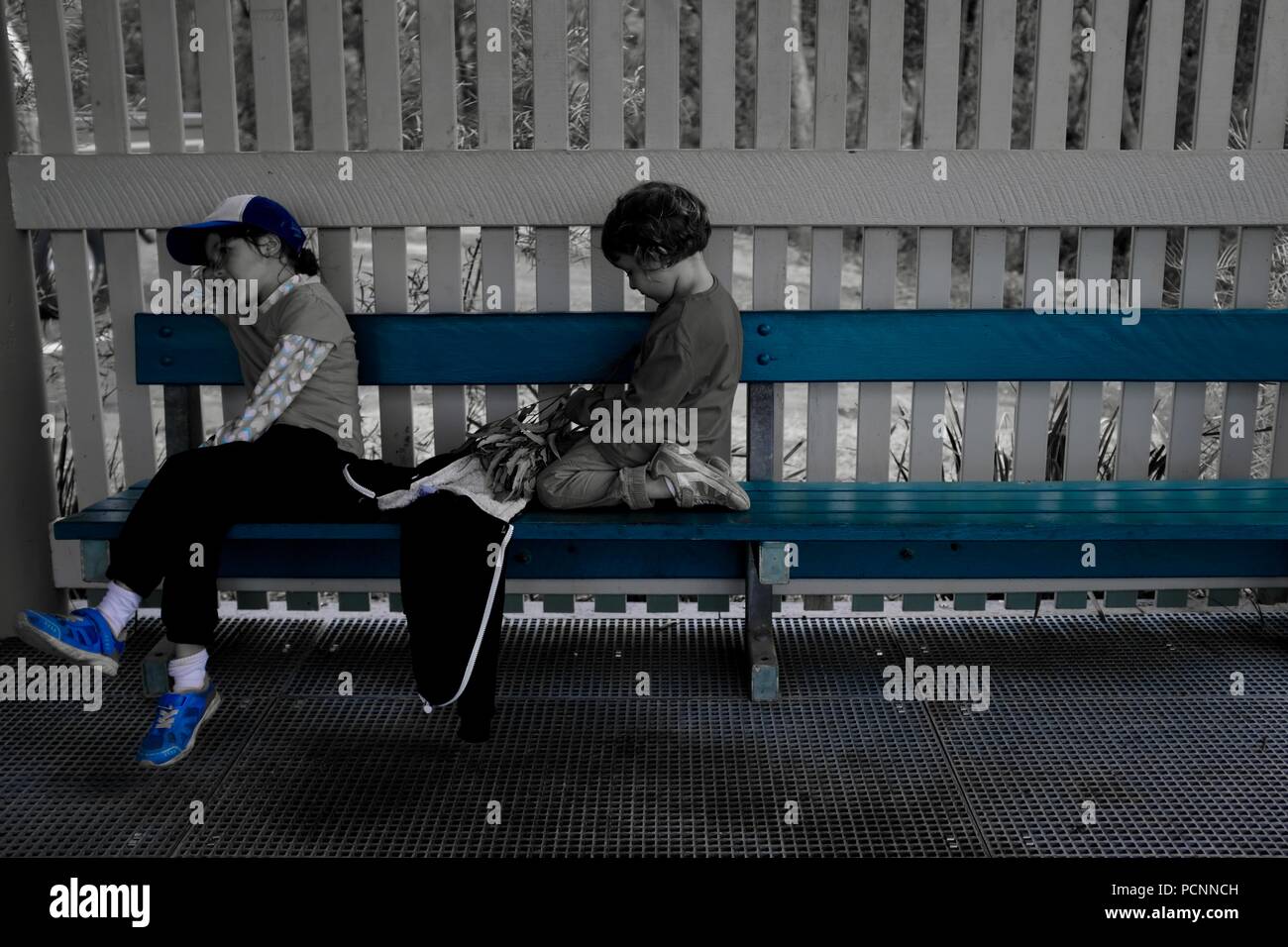 Dos niñas sentadas en un banco, filtro azul, Cardwell, Queensland, Australia Foto de stock