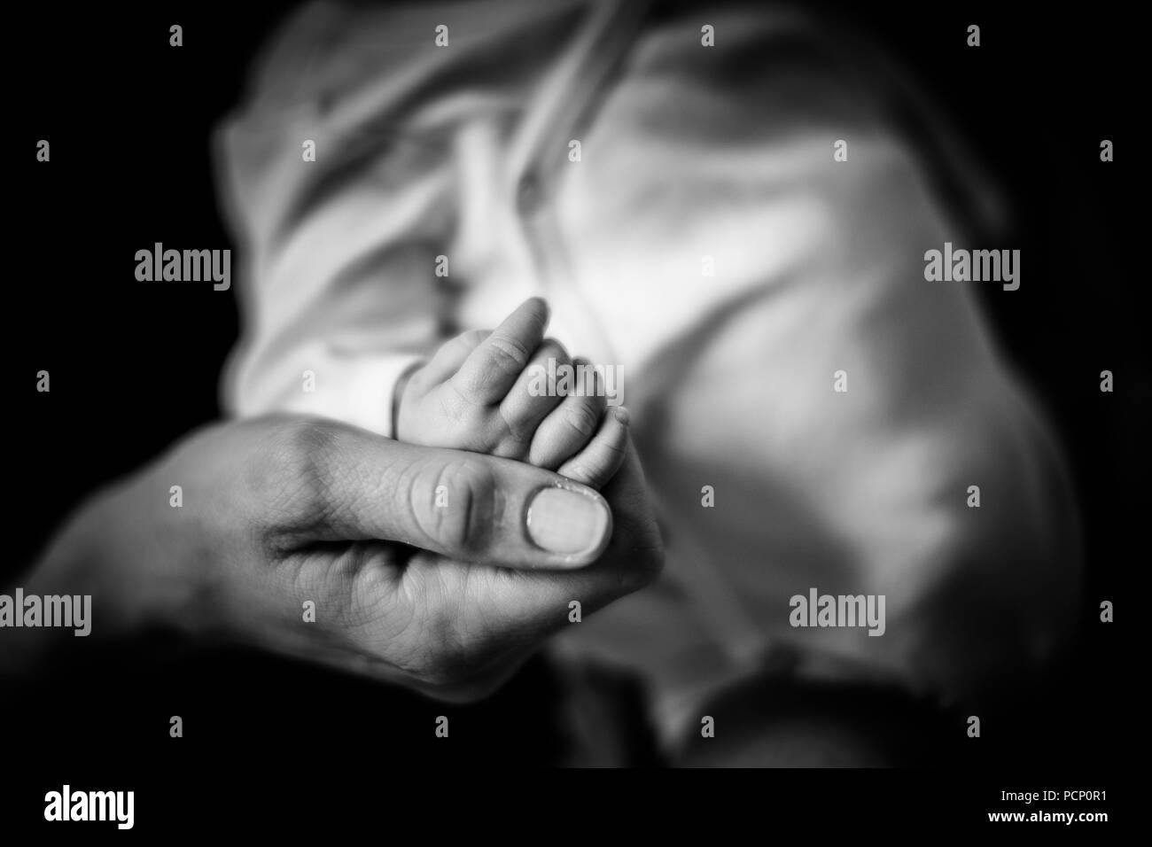 Madre sosteniendo a su bebé en la mano, suave, tierno, de cerca, el detalle, el Fondo fuera de foco, b/w Foto de stock