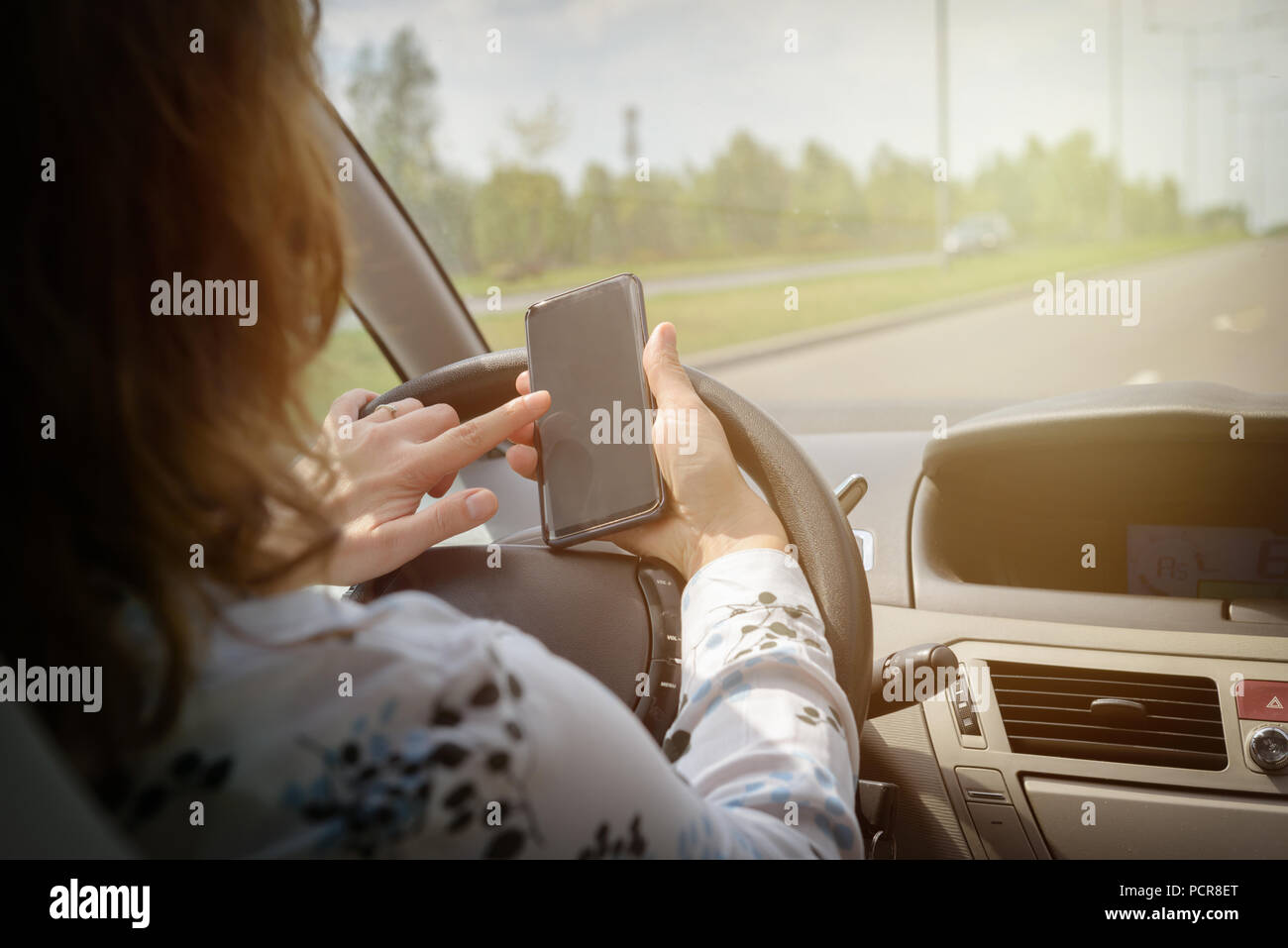Mujer usando el teléfono mientras se conduce el coche. Concepto de conductas arriesgadas Foto de stock