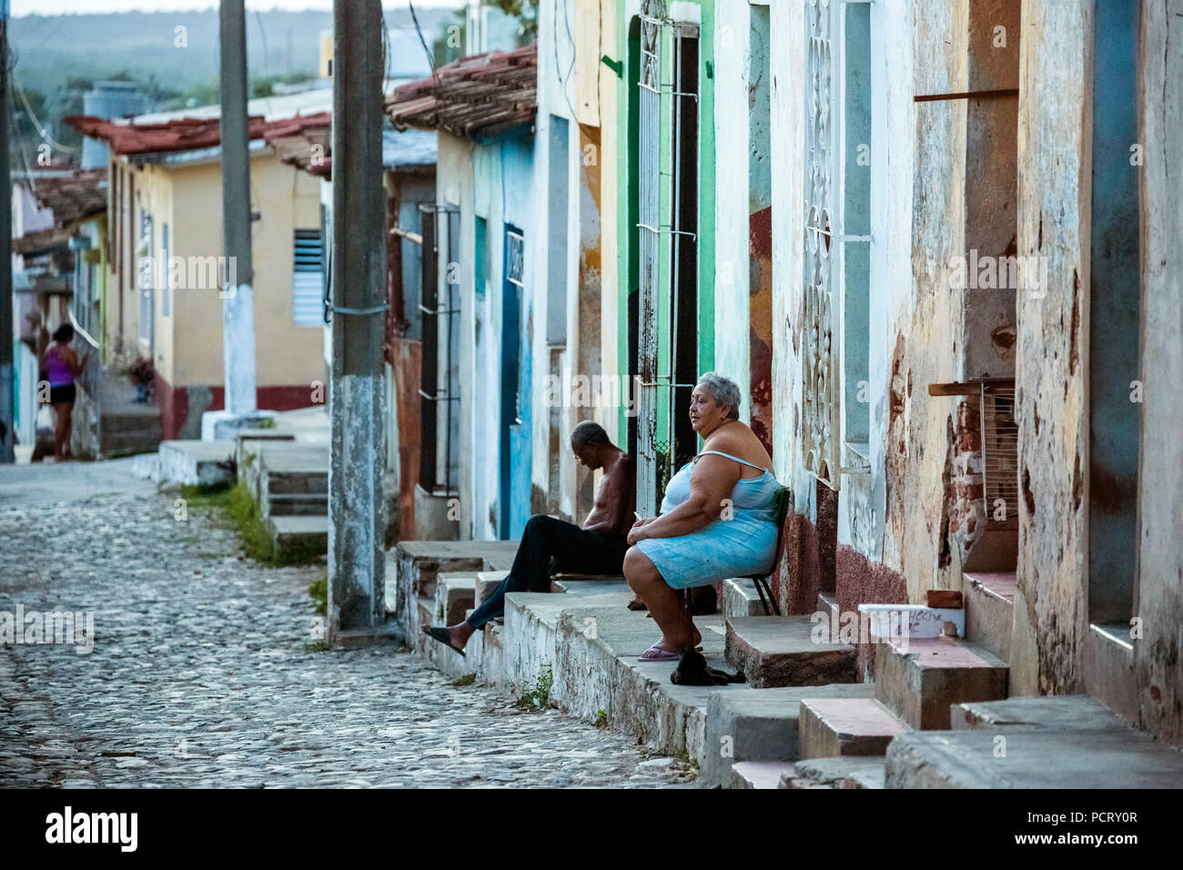 Los cubanos están sentados en sus pasos delante de sus casas en el centro histórico de la ciudad, escena callejera en el centro histórico de la ciudad de Trinidad, en Trinidad, Cuba, Sancti Spíritus, Cuba Foto de stock